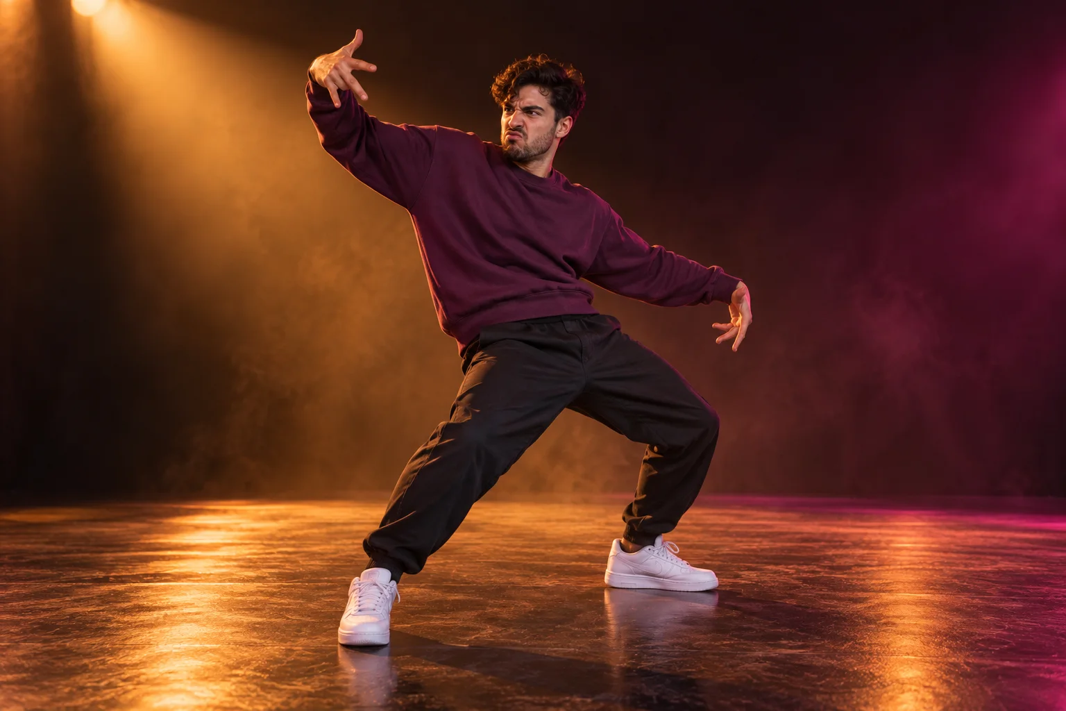 Foto horizontal de un hombre adulto con sudadera ciruela bailando bajo un foco de estudio